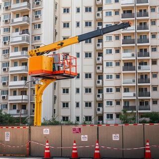 Hydra crane lifting an AC outdoor unit over a compound wall
